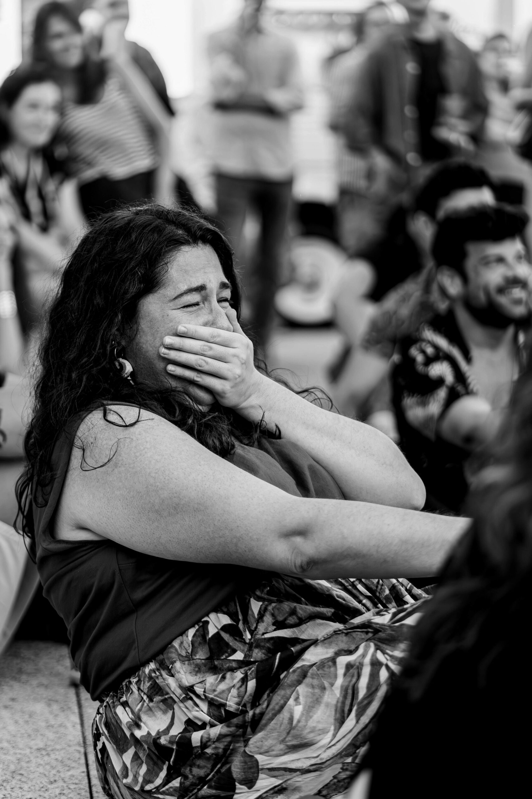 A woman with her hand over her mouth, caught mid-astonishment in an audience