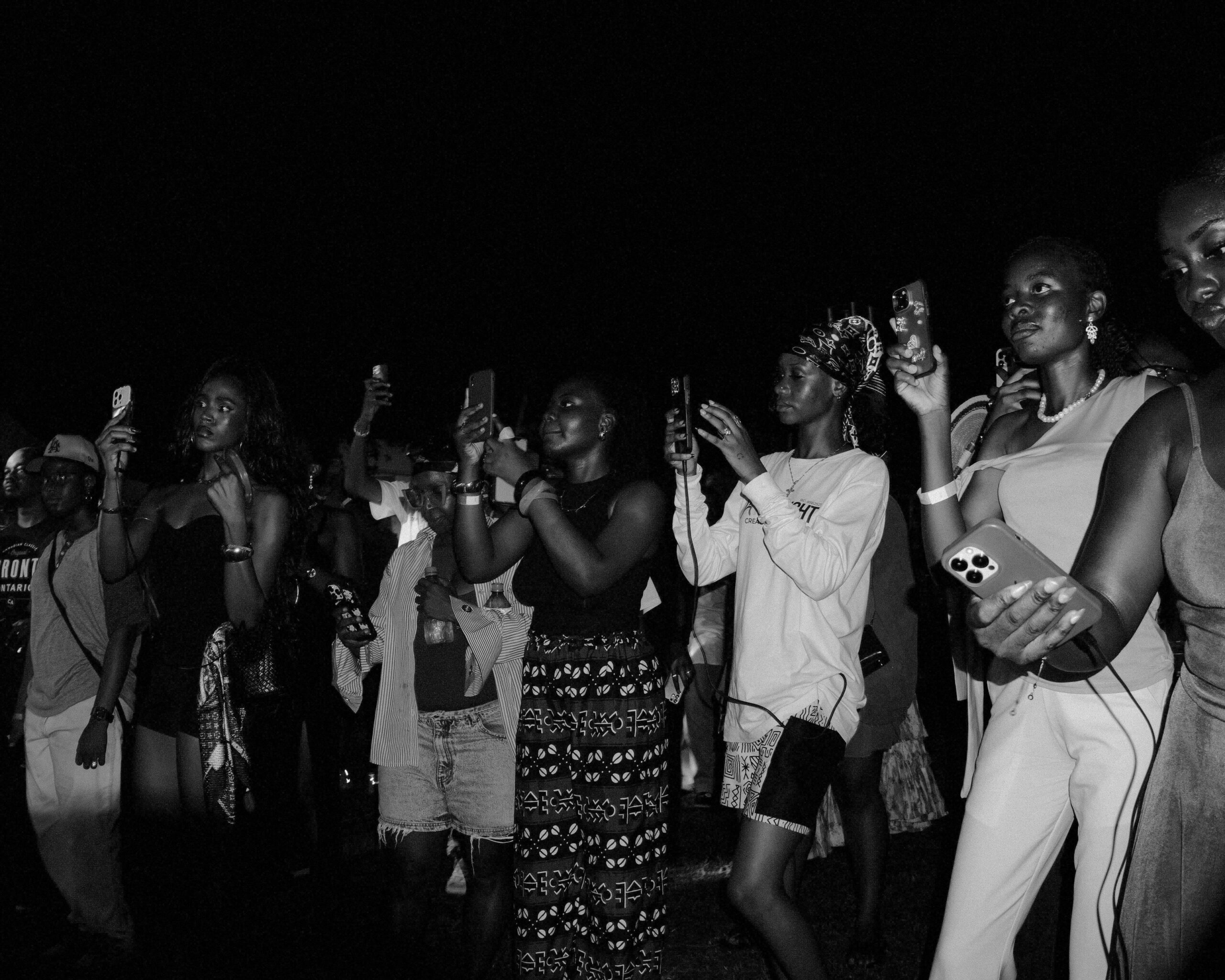 Students standing shoulder to shoulder, filming a performance on their phones